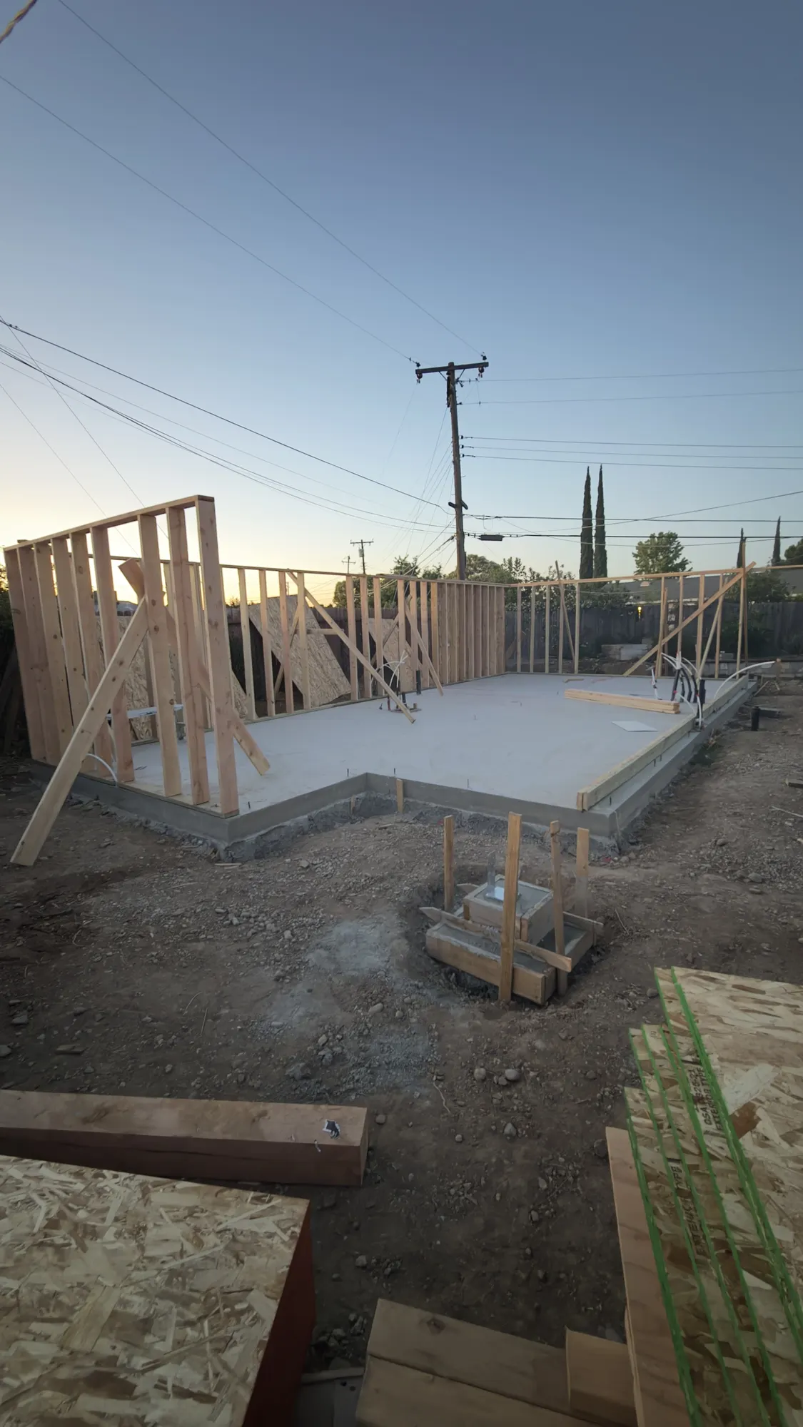 ADU walls framed at dusk on a poured slab during a Sacramento-region ADU build