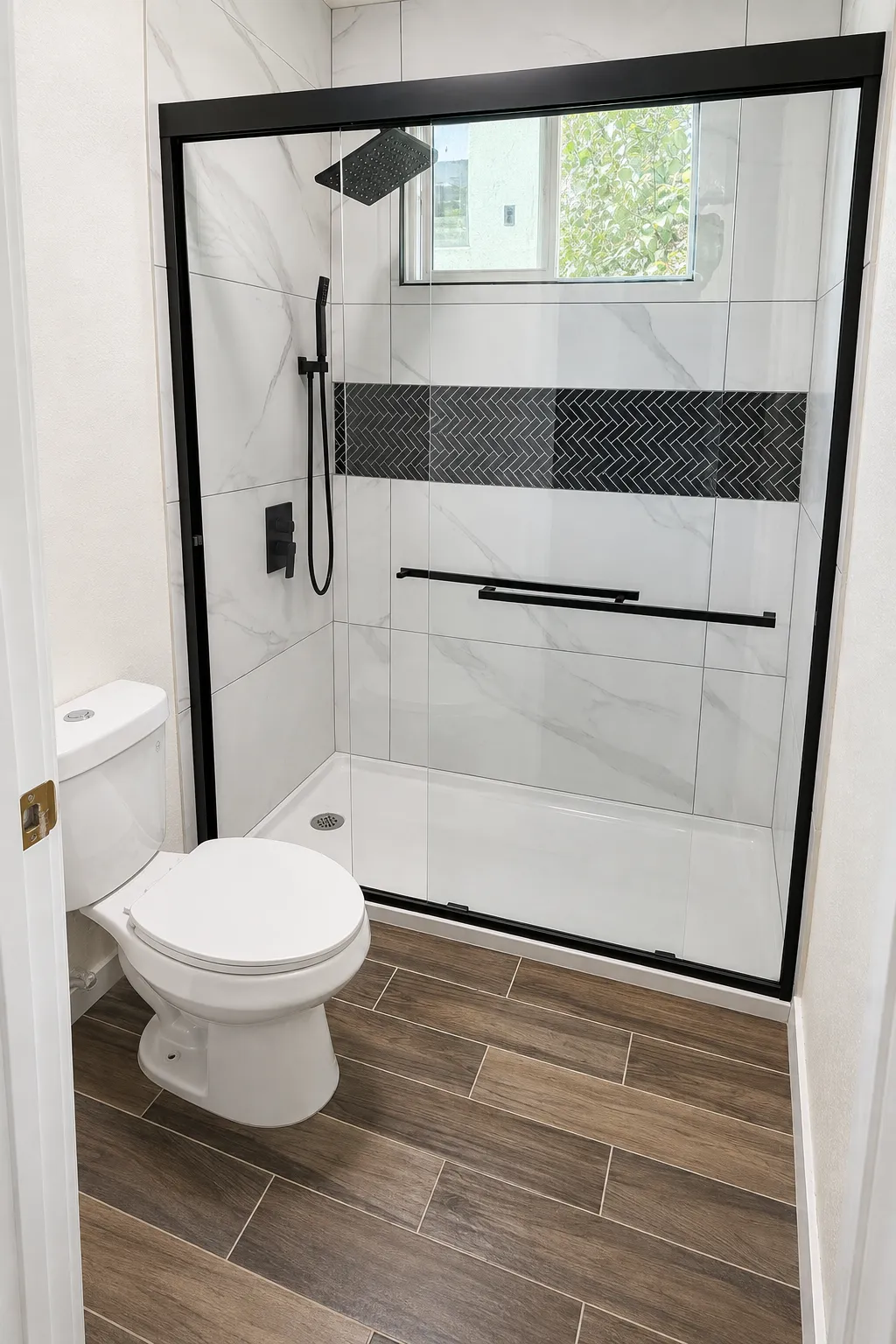 Remodeled bathroom with marble-look tile shower, black herringbone accent band, and wood-look flooring