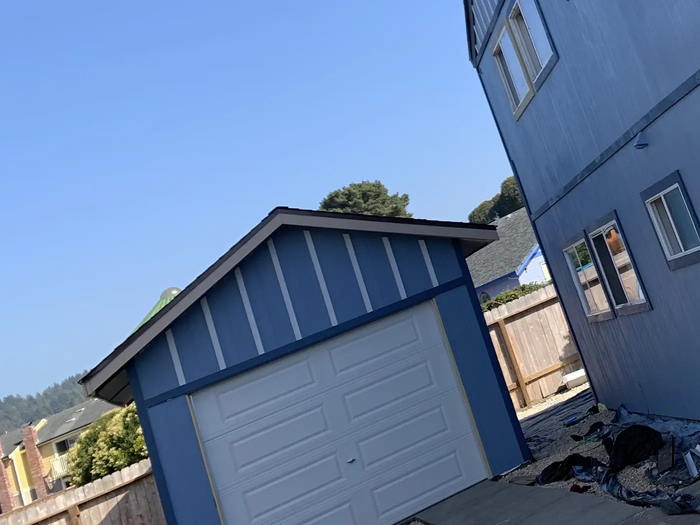 The new detached single-car garage finished in matching blue board-and-batten with a white roll-up door
