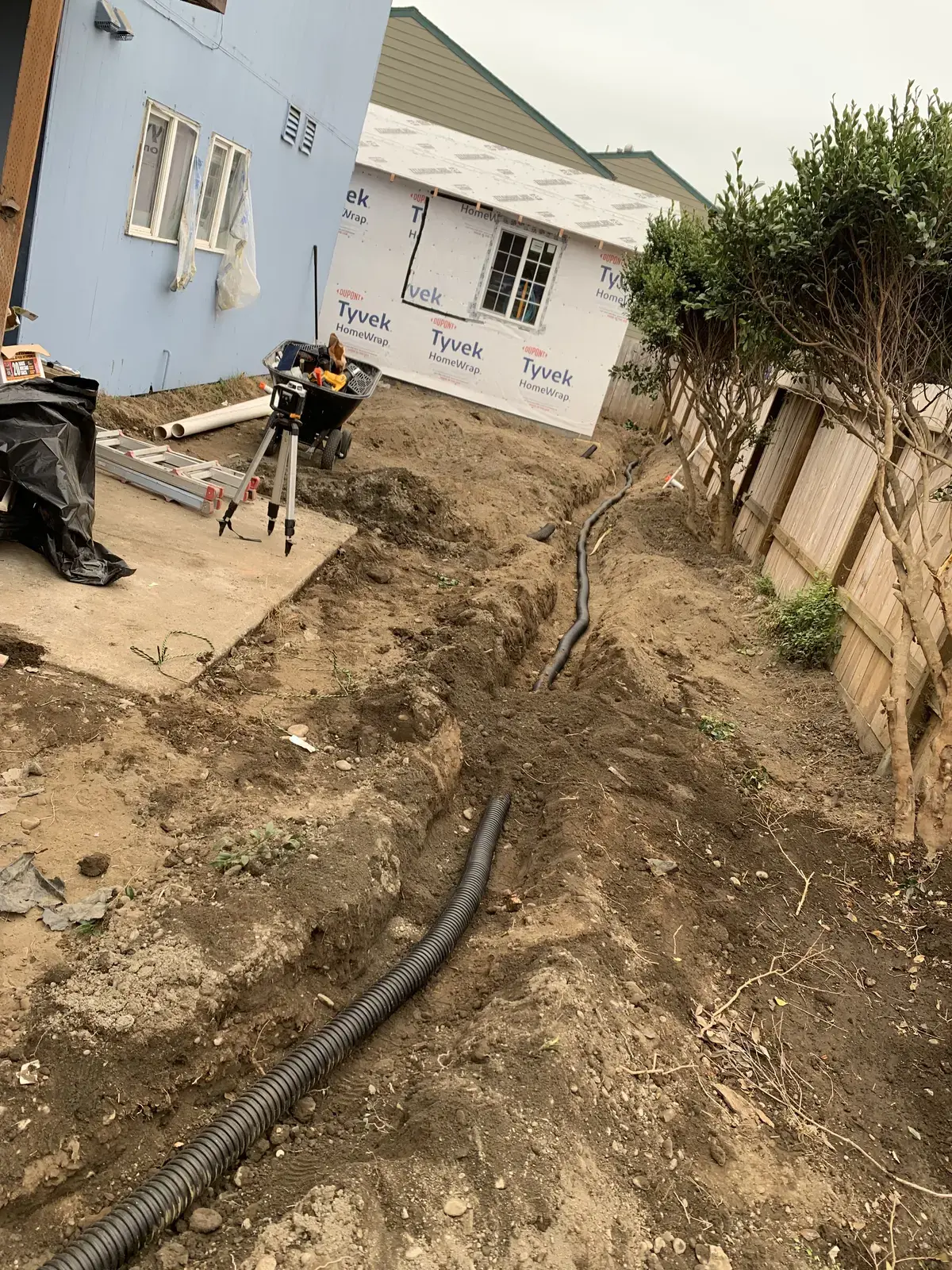 Perforated drain pipe laid in an open trench alongside the building