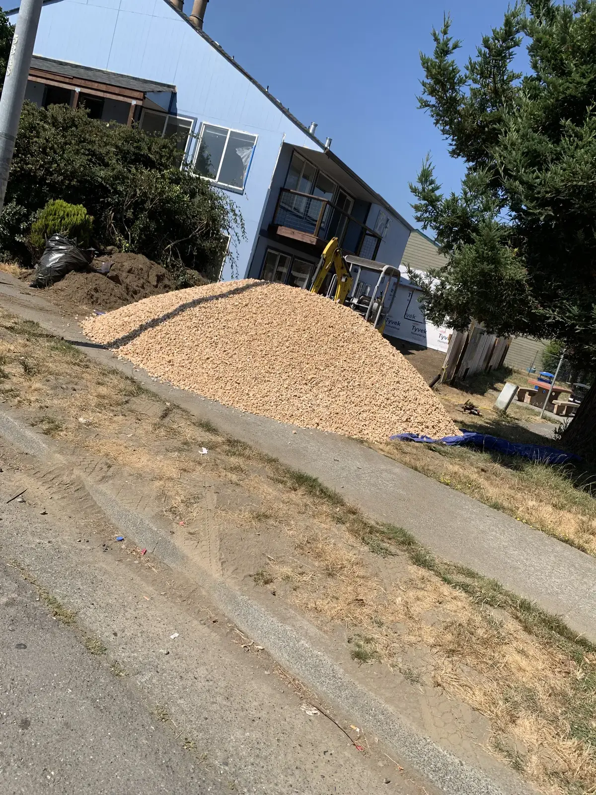 A dump truck load of drain rock piled on the street for the drainage system