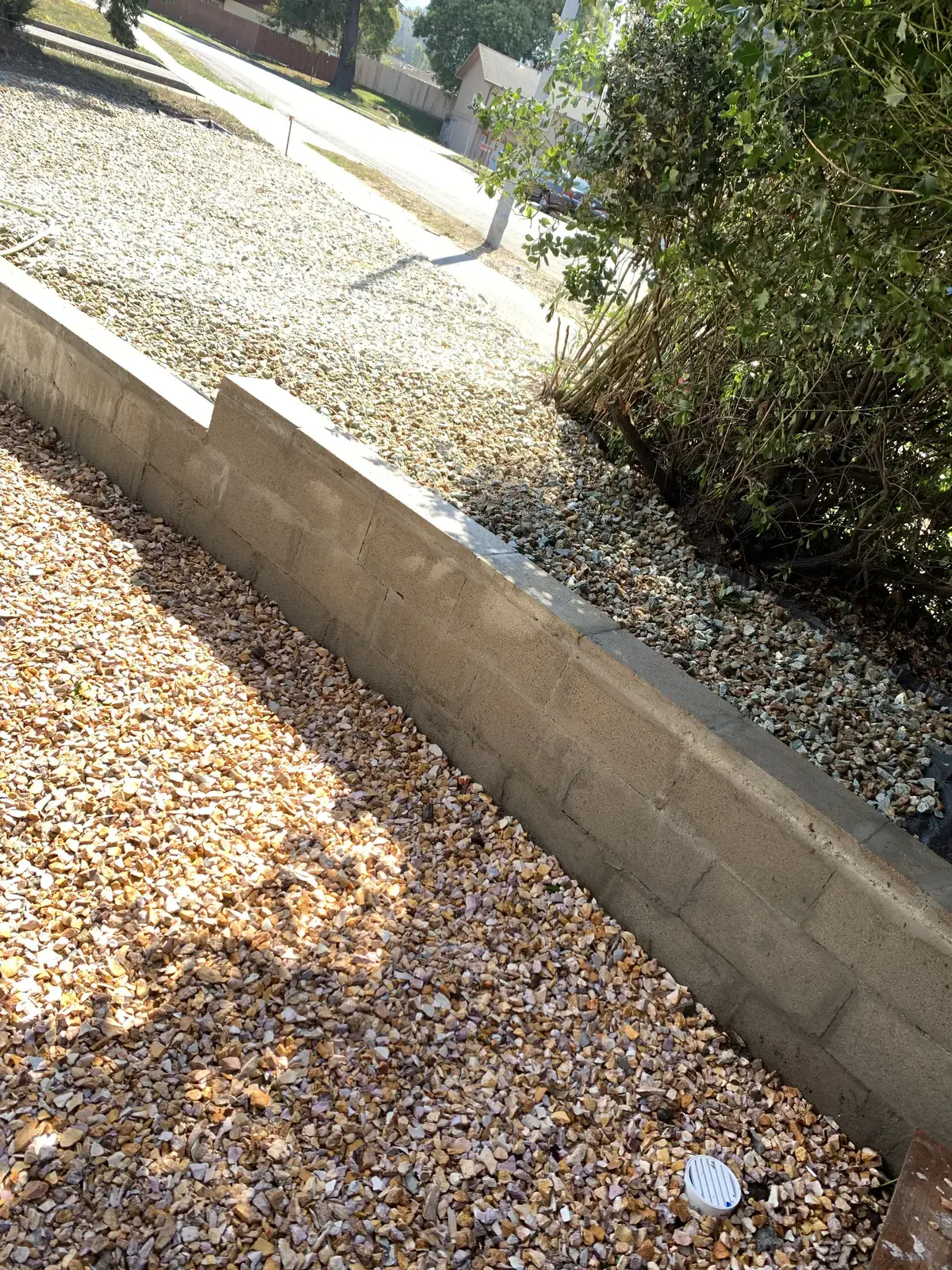 Finished drain rock swale against the block retaining wall with the drain grate set