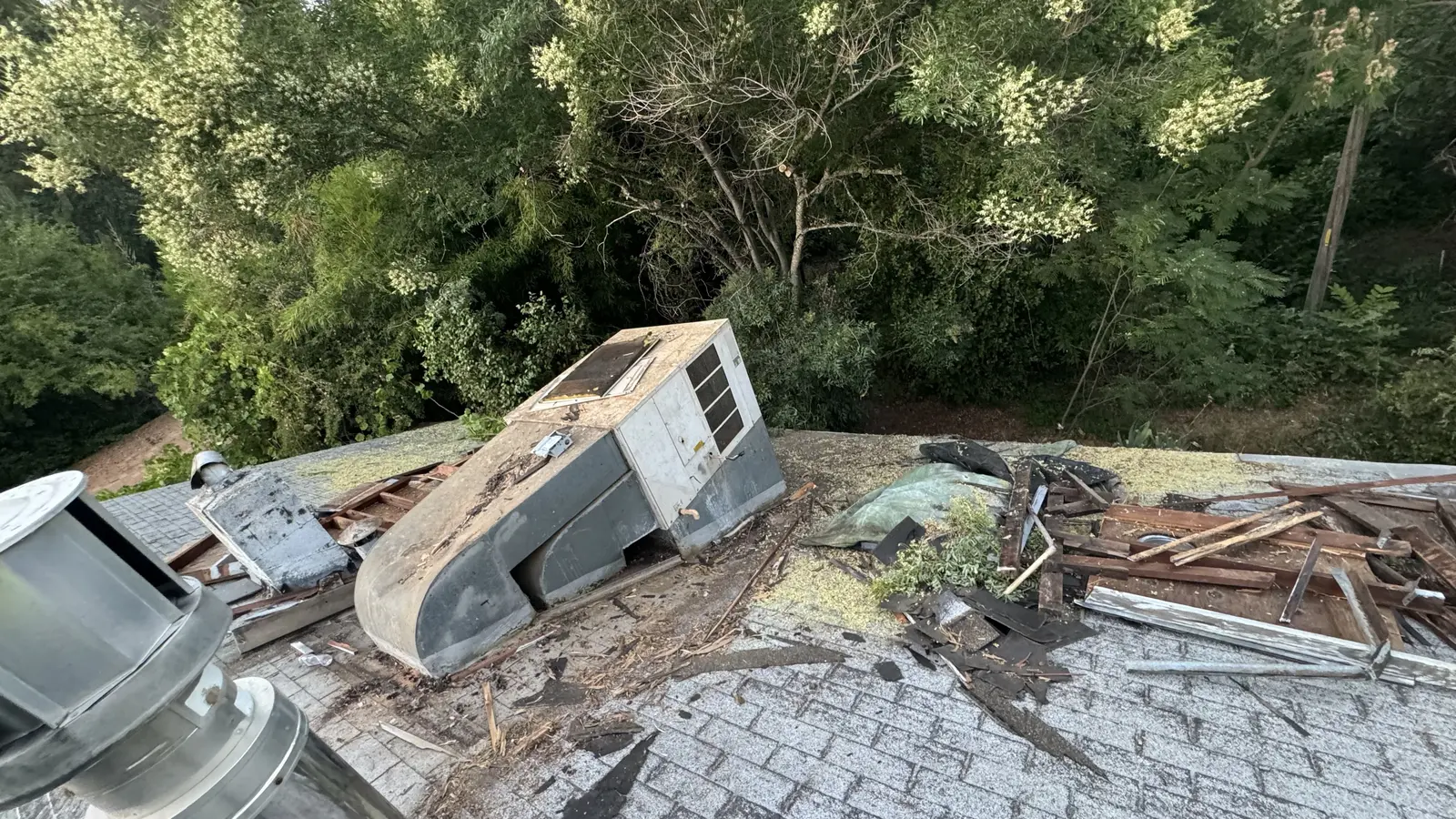 The old rooftop air conditioning unit on the ground after removal, surrounded by tear-off debris