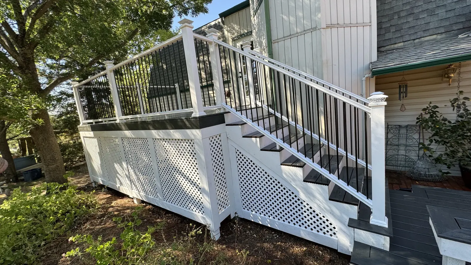 Finished deck and stair with white railing, black balusters and white lattice skirting