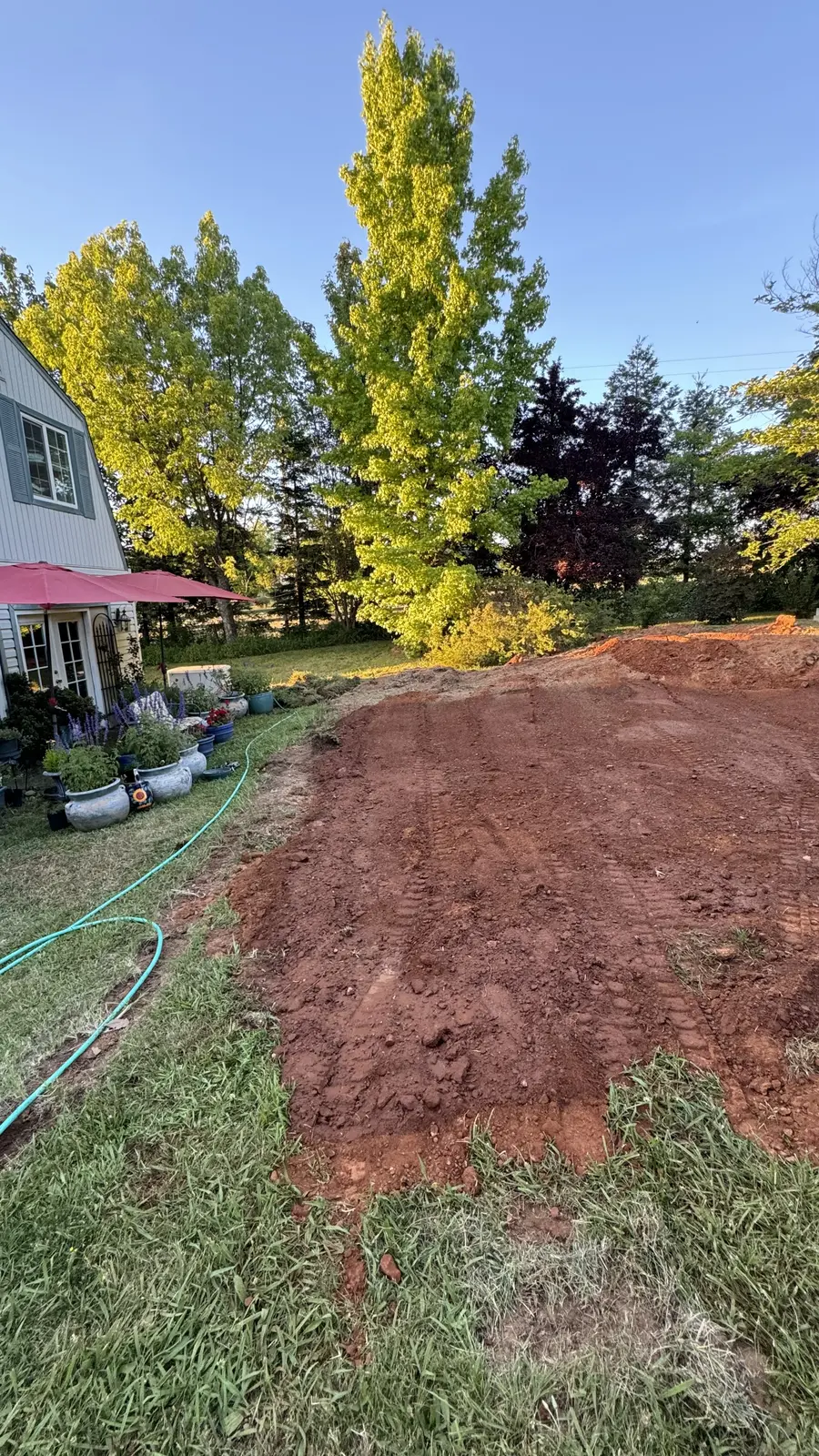 First cut through the lawn, raw graded soil where the ground used to slope toward the house