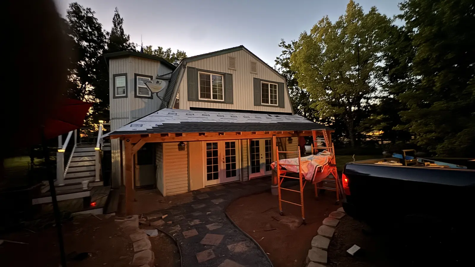 The new heavy-timber covered porch roofed and lit at dusk with the paver patio below