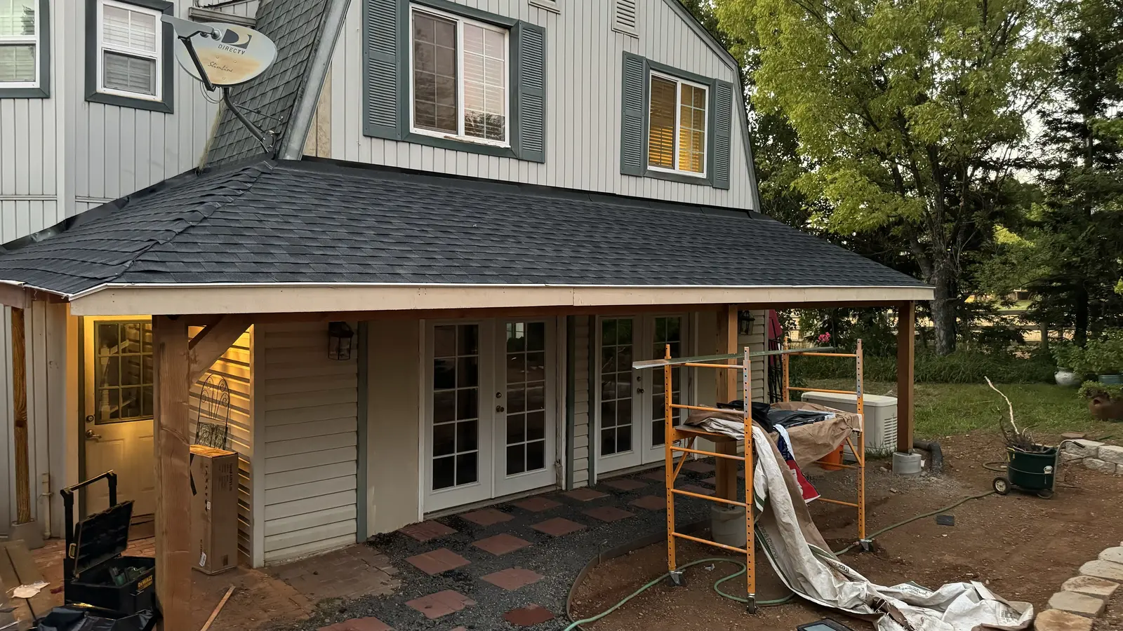 The finished porch shingled with columns wrapped and lights on at dusk