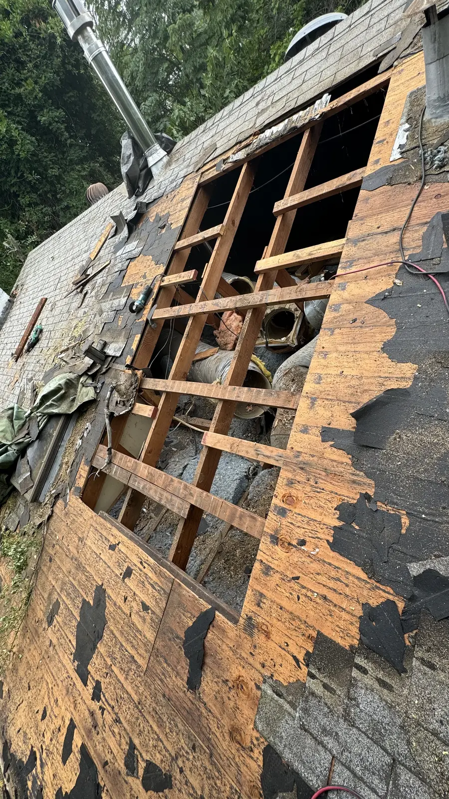 The roof opened up, shingles stripped back to bare rafters and skip sheathing where the air conditioner had sat