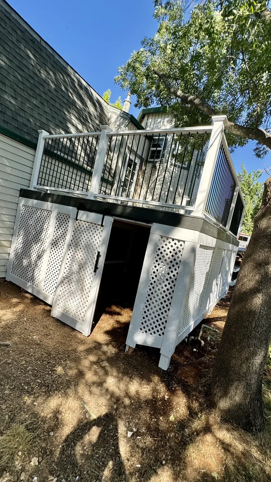 Under-deck storage room with its access door standing open in the lattice skirting