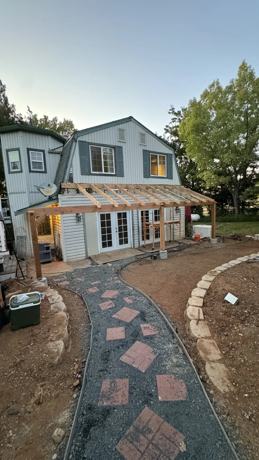The completed paver walkway and set stone border at dusk, with the new porch still framed above it