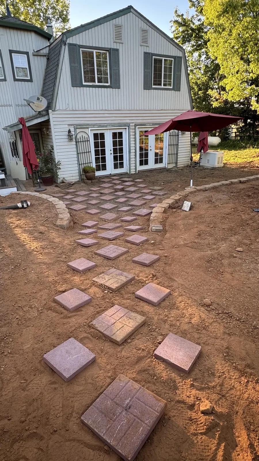 Pavers laid out loose on bare dirt to plan the walkway run