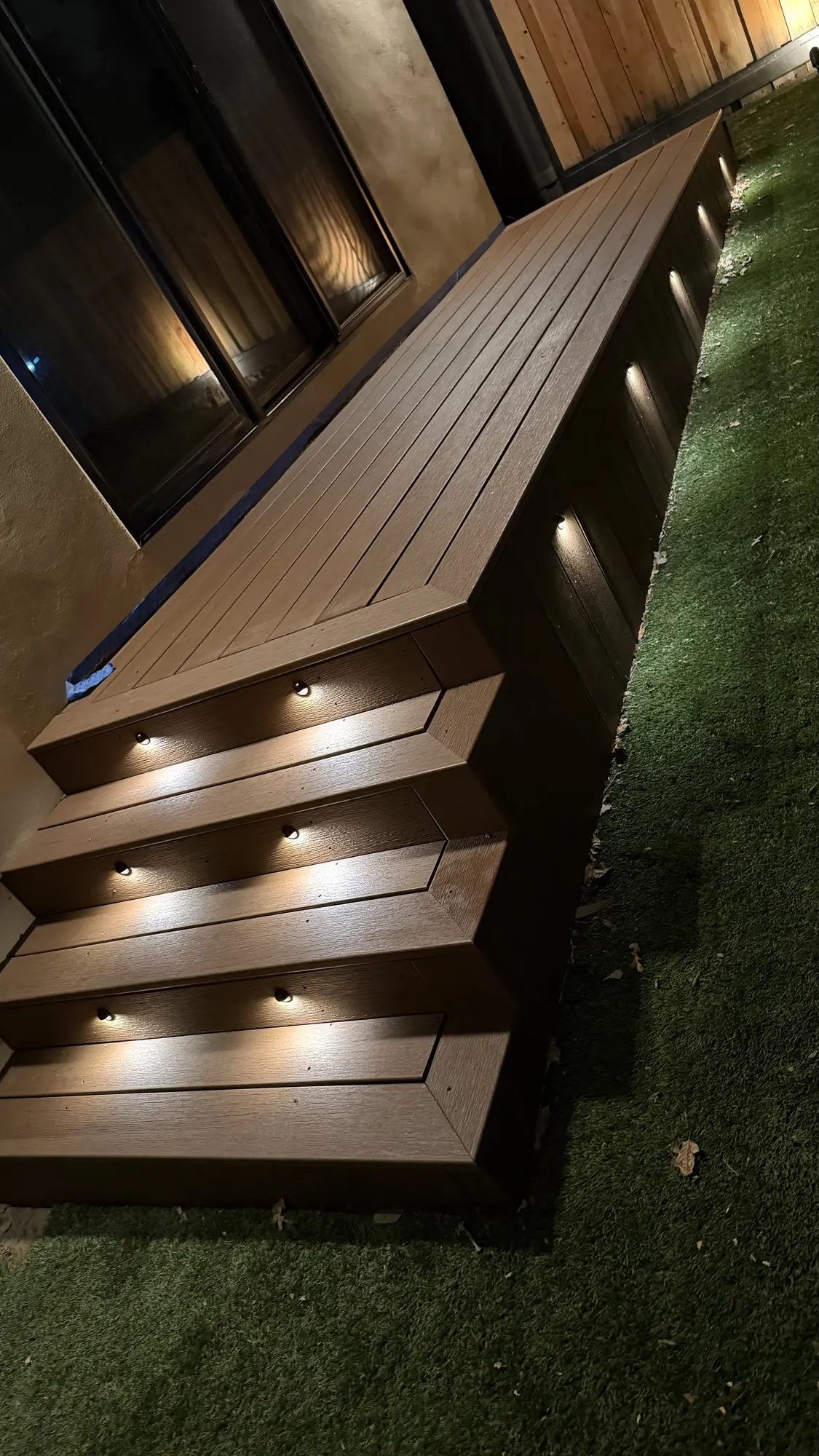 Composite deck stairs with low-voltage riser lighting at night on a Sacramento property