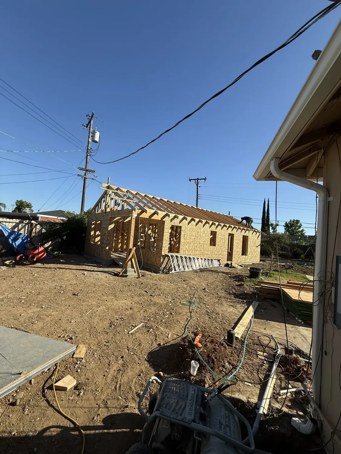 Roof rafters and roof sheathing being installed on the ADU, carpenter working on the roof deck